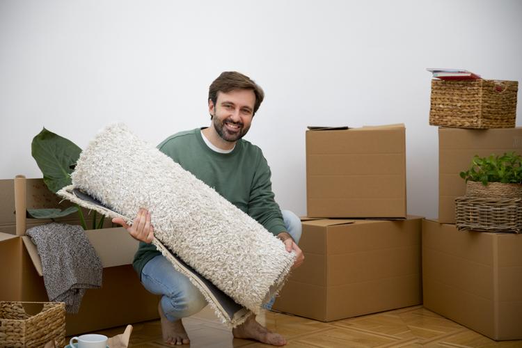 A man holds a rug he's preparing to pack in front of packed boxes